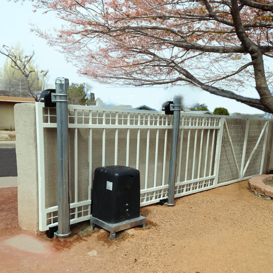 white slide gate with automatic opener in gravel yard with adobe wall. gate design has grid series of 2 rows of squares at top, vertical bars below then section of 2 rows of squares at bottom