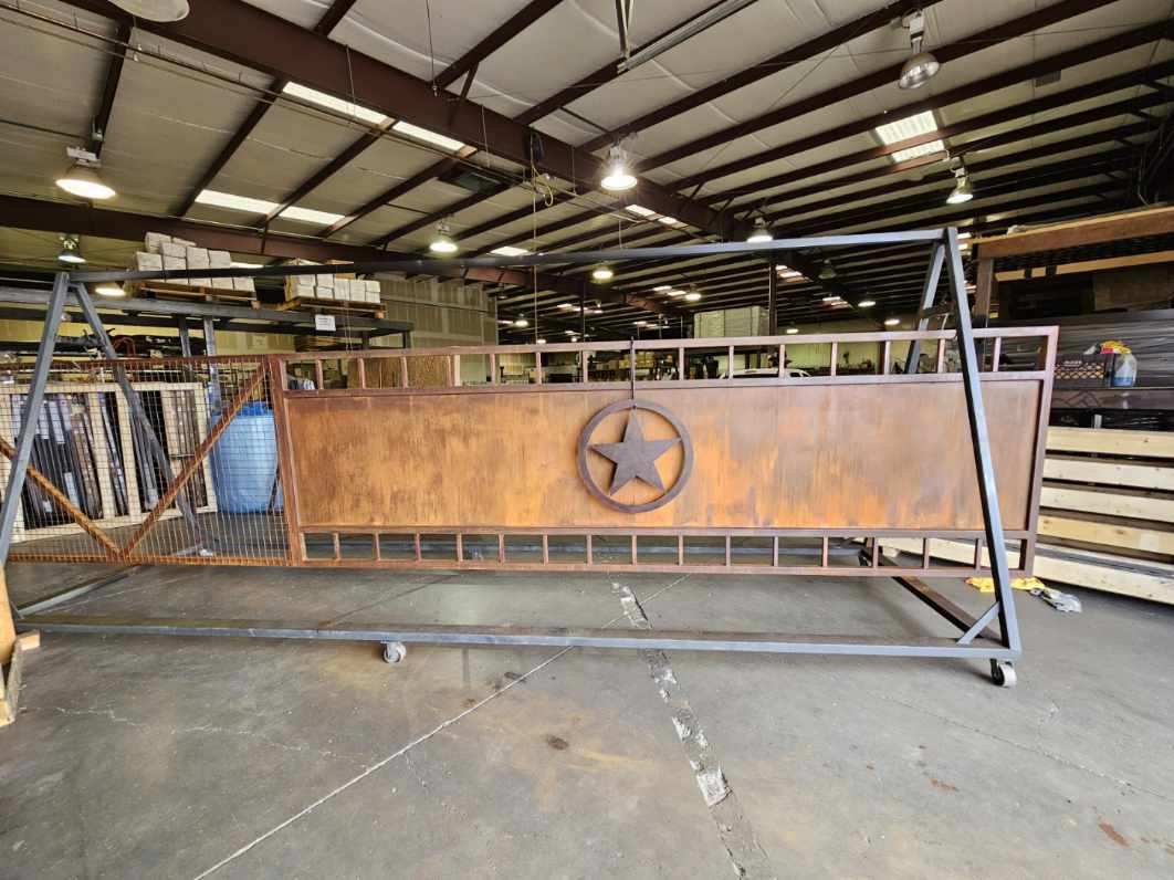 rust tone metal driveway gate in factory with large circled star applied to center