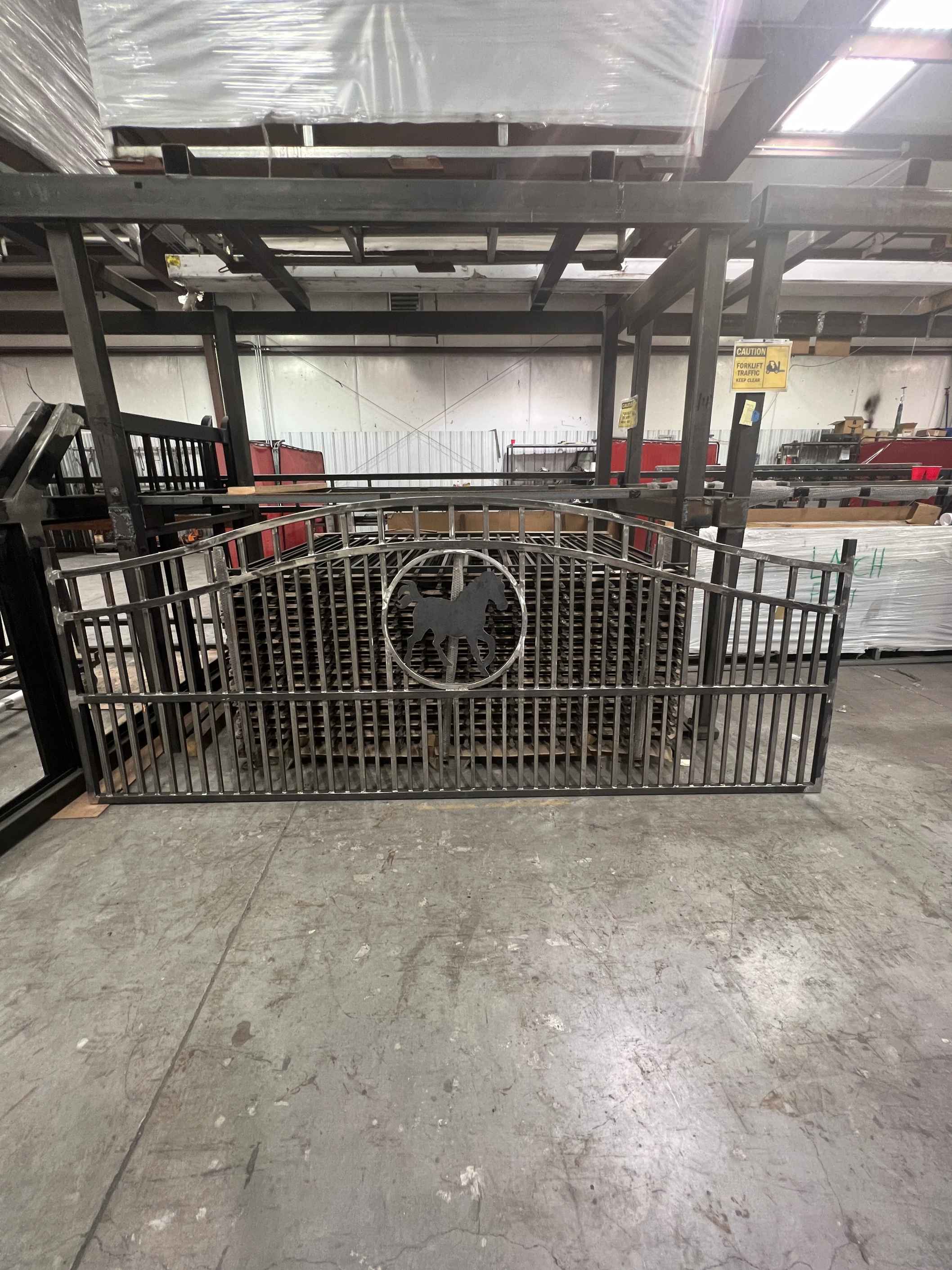 arched raw metal gate in factory with cutout horse image applied