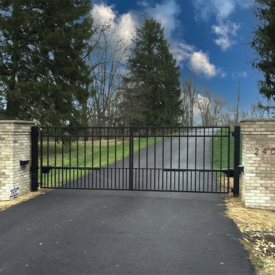 black metal double gate with simple grid topper between brick pillars at end of long road surrounded by trees