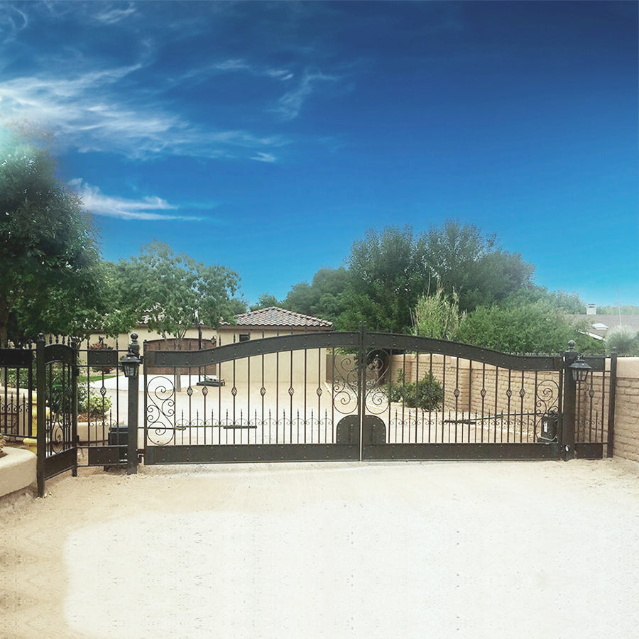 ornate arched black wrought iron double gate installed in adobe brick wall in front of adobe home with tile roof