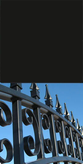 Close-up of a Jet Black color surface above a black metal gate with decorative scrollwork and spear-shaped finials.
