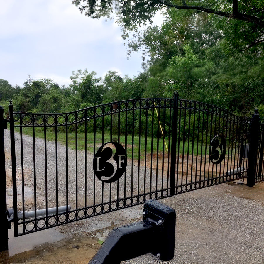 Double black Sonoma style iron gate on driveway with circle with laser cut monogram "L3F " in center of each gate