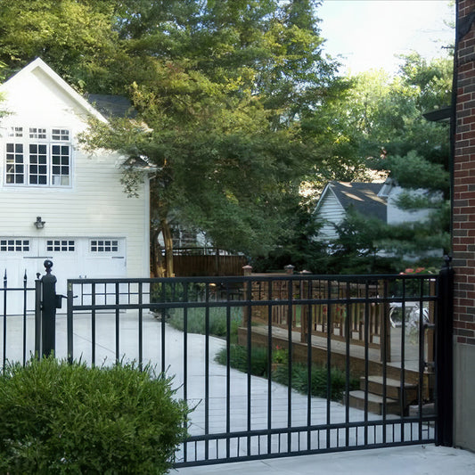 Athena style black wrought iron single gate is geometric design, attached to brick house and iron fence with garage cottage and deck behind it