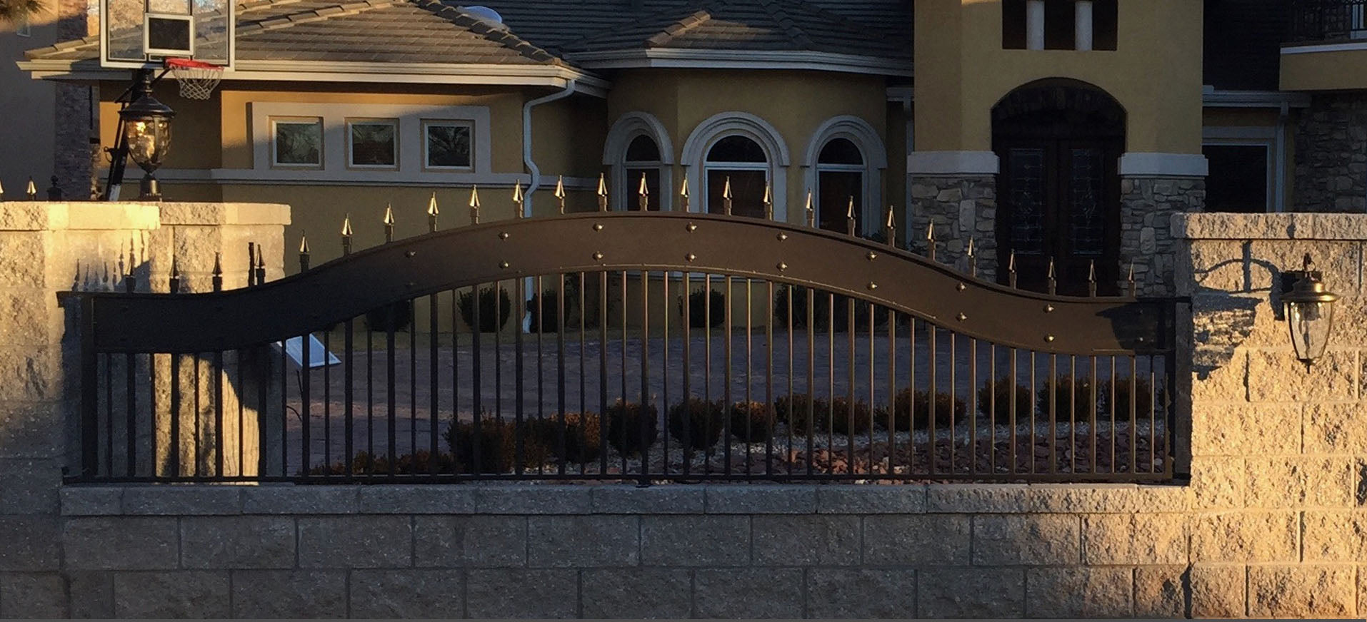 formal bronze color steel fence with spear point finials in stone wall